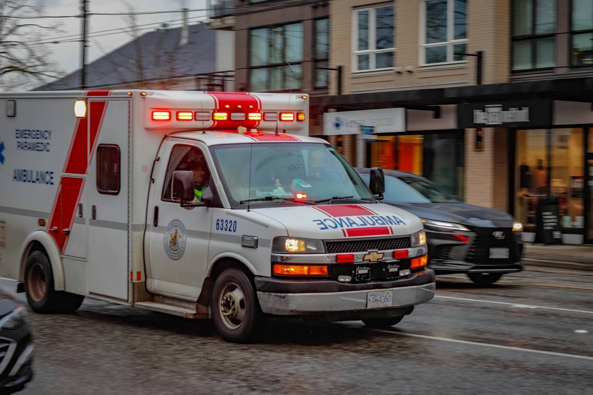 Ambulance rushes to an emergency call with flashing lights and sirens. BC Ambulance Service vehicle in Vancouver Canada.