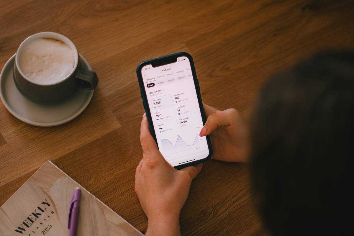 Checking finances on a phone with coffee.