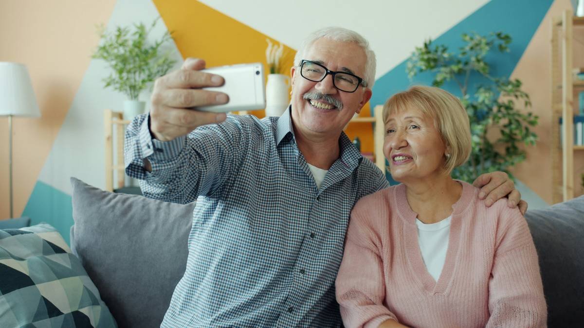 Cheerful old couple lady and man are having fun with smartphone looking at screen laughing enjoying media. Communication and elderly people concept.